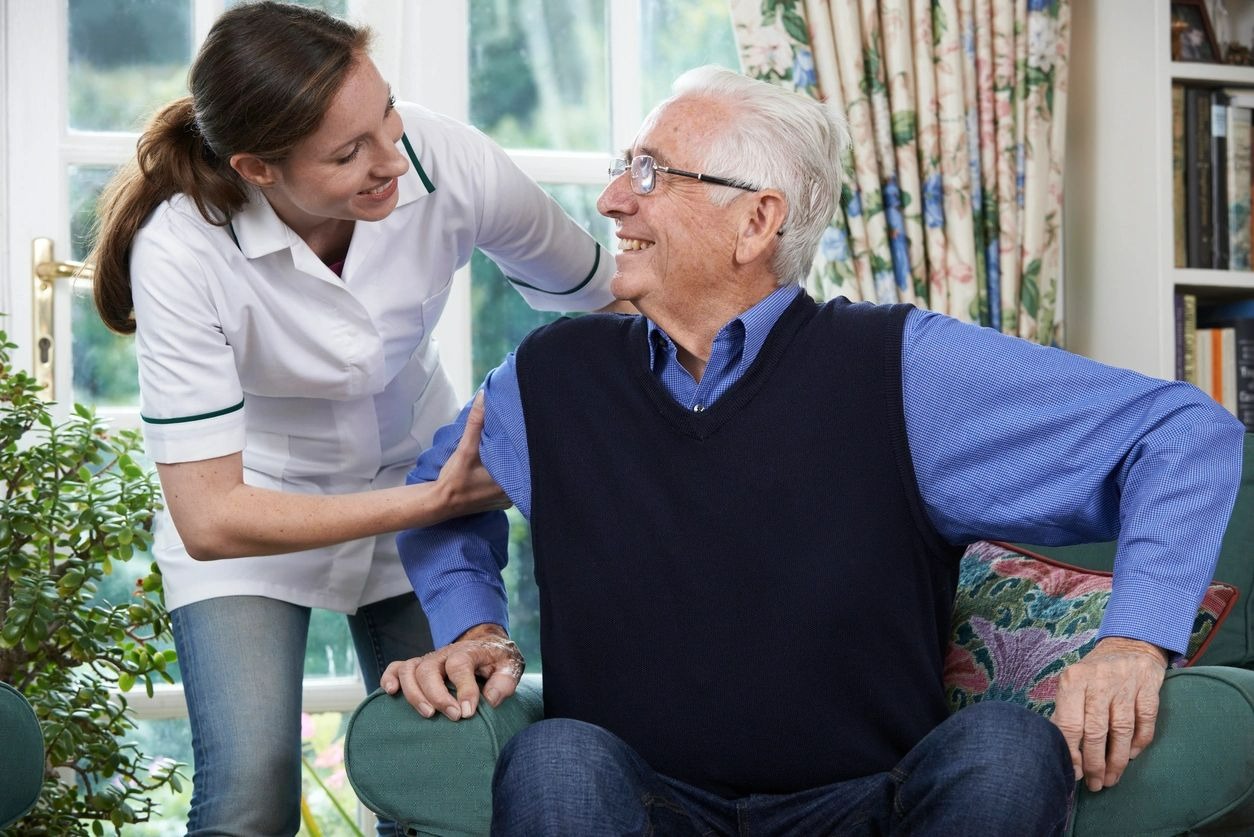 Care Worker Helping Senior Man To Get Up